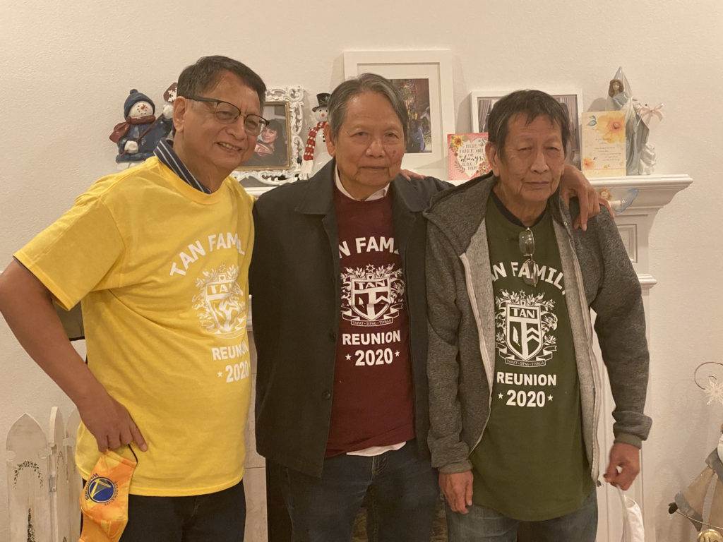 Three men posing indoors, wearing casual colorful shirts and jackets.