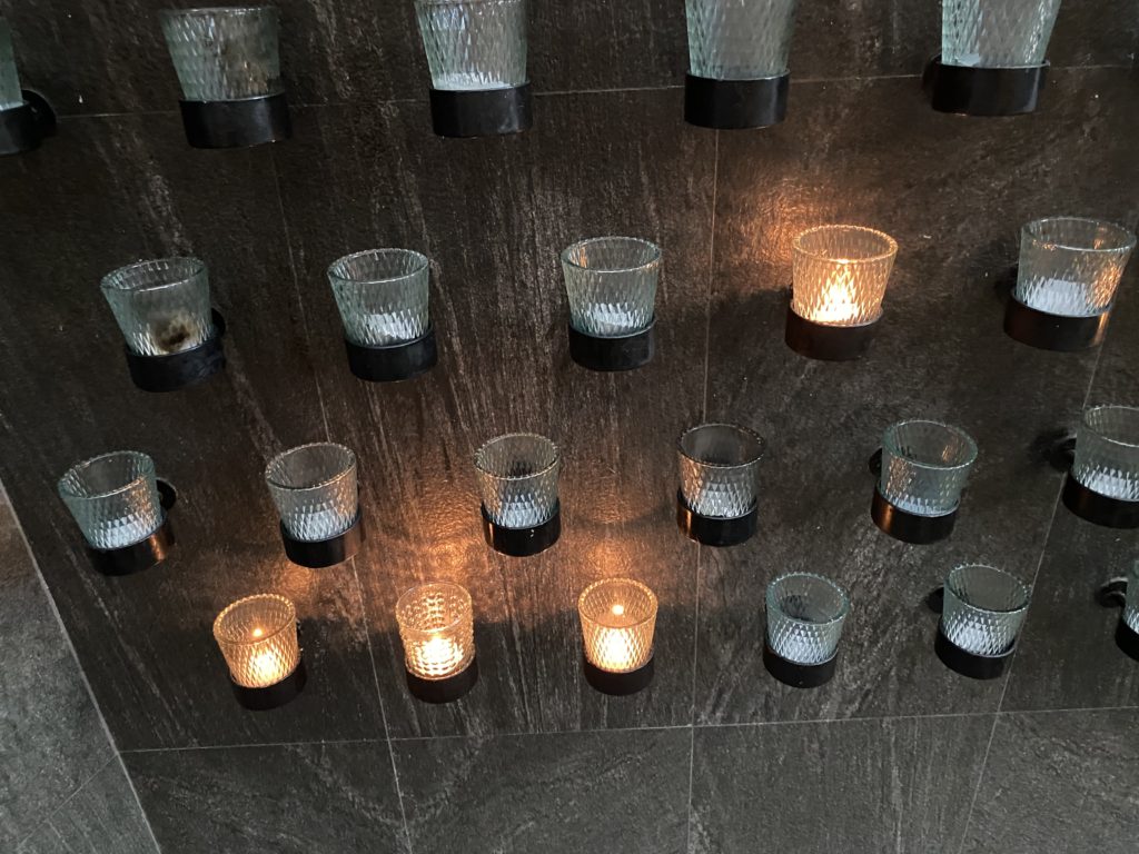 Lit candles and empty holders on a dark surface.