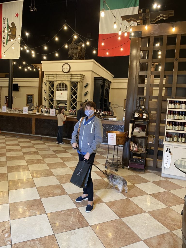 Person wearing a mask and casual outfit indoors with luggage.