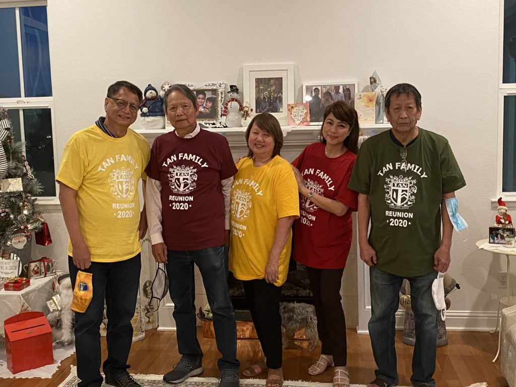 A group of five people wearing colorful event T-shirts posing indoors.