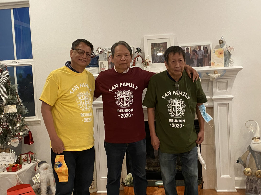 Three men posing together wearing colorful t-shirts indoors.