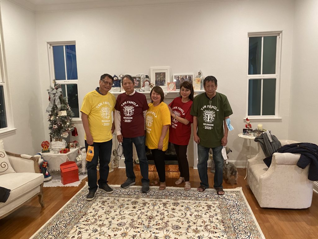 Group of six people posing indoors by a decorated Christmas tree.