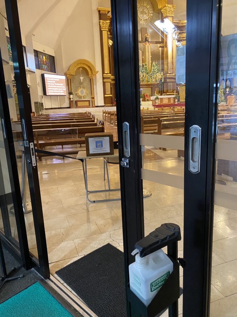 Open glass doors reveal a quiet church interior with wooden pews and ornate altar.