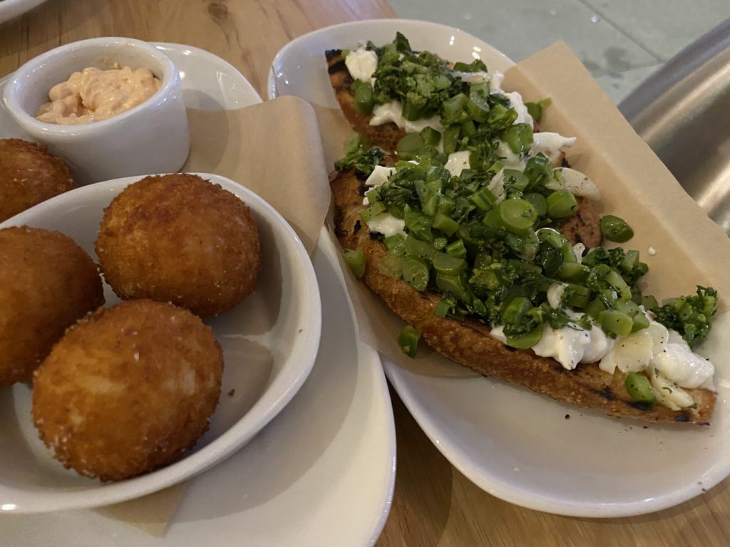 Delicious fried balls with a side of toast topped with cream and herbs.