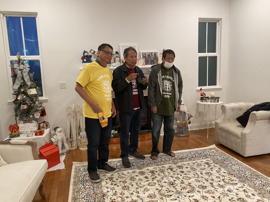 Three men standing together inside a cozy living room.