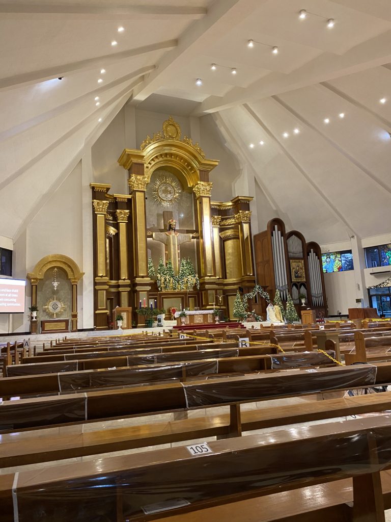 Interior of a church with ornate altar and wooden pews.