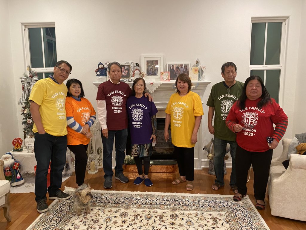 Group of six people wearing colorful matching shirts, posing indoors.