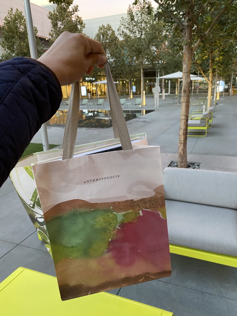 Person holding a colorful reusable shopping bag outdoors.