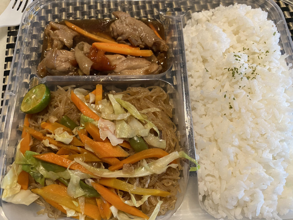 A meal tray with rice, fried chicken, and stir-fried vegetables.
