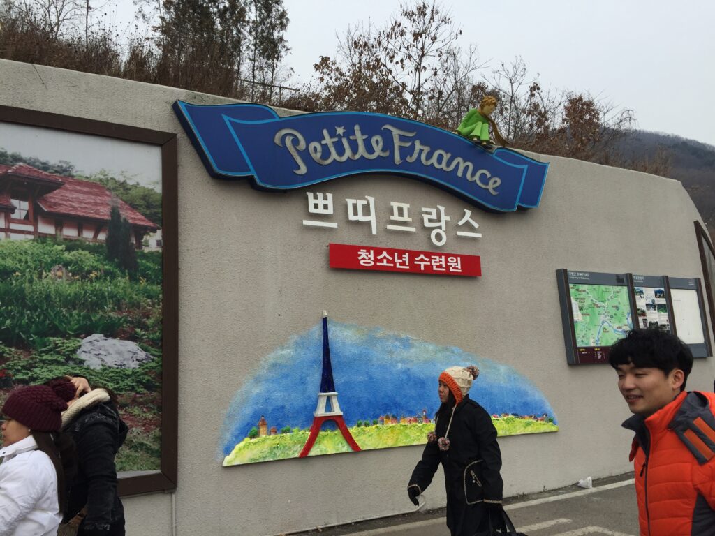 A person walks past a wall mural featuring the Eiffel Tower and the words 'Petite France'.