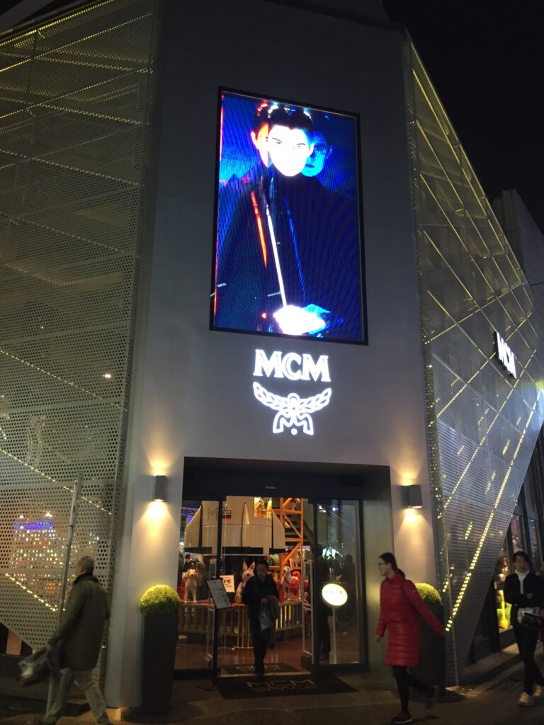 Night view of an MCM store with a large digital billboard above the entrance.